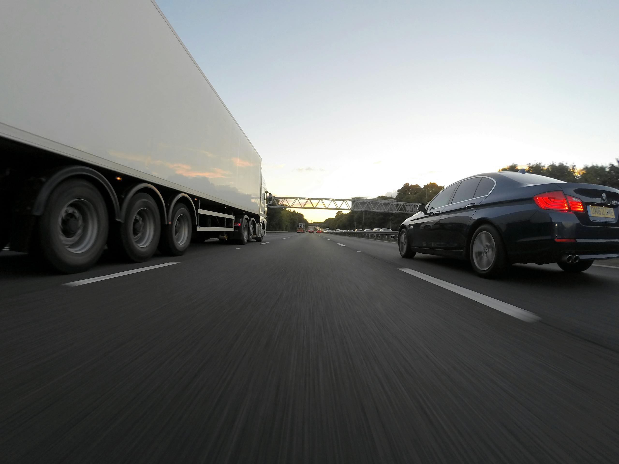 Cars and a truck speed along a highway under the clear sky, showcasing transportation dynamics.